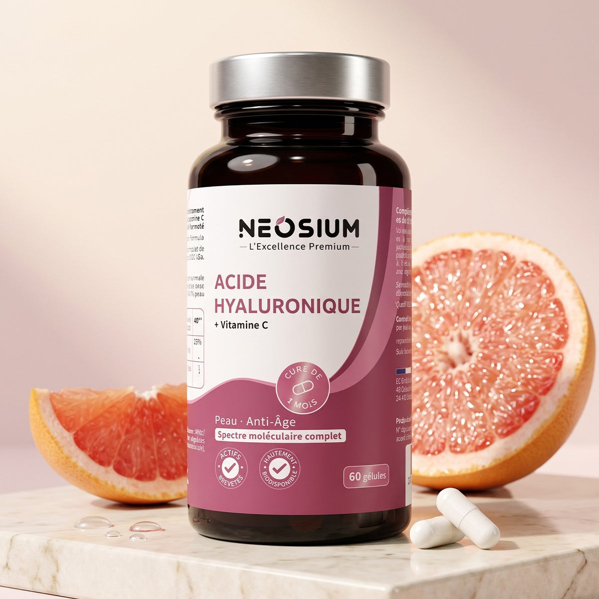 Flacon de gélules d'acide hyaluronique Neosium à spectre moléculaire complet avec vitamine C, posé sur du marbre à côté d'un pamplemousse frais.